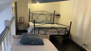 A bedroom with two beds, a chair, and a bedside table. - Rent studio 4 persons sea and city center (Le Grau-du-Roi)