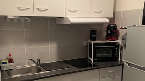 A kitchen with white cabinets, a sink, a microwave, and a Bosch coffee maker. - Rent studio 4 persons sea and city center (Le Grau-du-Roi)