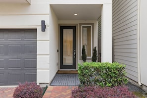 A modern house with a garage, a front door, and a small porch area. - Gated Modern Home in Independence Heights! (Houston)