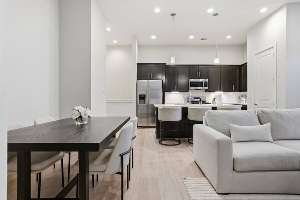 A modern kitchen with dark cabinets, stainless steel appliances, and pendant lighting. - Gated Modern Home in Independence Heights! (Houston)