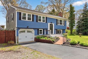 A two-story house with a garage, a front porch, and a well-maintained lawn.