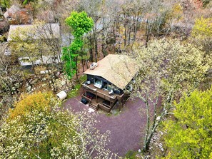 Ein modernes Haus mit einer Terrasse, umgeben von Bäumen und einer Schotterauffahrt.