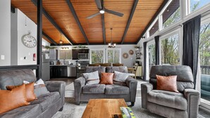 Un vaste espace de vie agrémenté d’un ventilateur de plafond, d’une table basse en bois et d’un ensemble de canapés.
