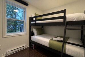 Een stapelbed met wit beddengoed en groene kussens in een kamer met een raam.