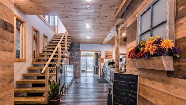 Ein Holzinnenraum mit Treppe, einer Tafel mit Veranstaltungsdetails und einer Blumenkomposition.