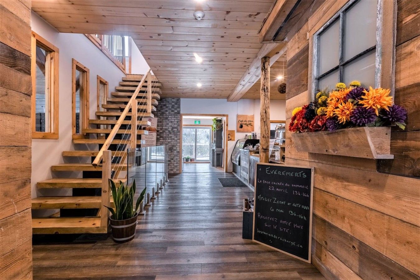 Ein Holzinterieur mit einer Treppe, einem Kreidetafel-Schild und einer Blumenkomposition.