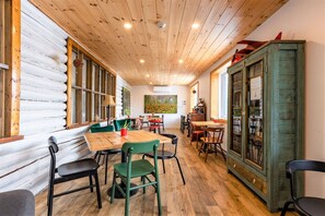 Un comedor acogedor con mesas y sillas de madera, un cuadro grande en la pared y un aparador de madera rústica.