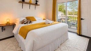Une chambre d’hôtel avec un lit, une table de chevet avec une lampe, une fenêtre avec des rideaux et une vue sur l’extérieur.