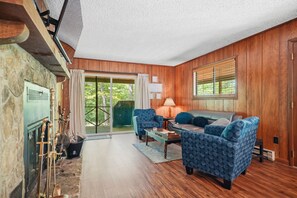 Ein gemütliches Wohnzimmer mit Kamin, Holzwänden, einer Couch und einem Couchtisch.