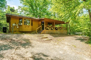 Eine Holzhütte mit Veranda, Satellitenschüssel und einem Schotterweg.