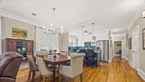 A spacious dining area with a wooden table and chairs, a kitchen with modern appliances, and a hallway leading to other rooms. - Elegant Home in Prime Location/ Close to Universities, Hospitals, Parks and Stadiums (Atlanta)