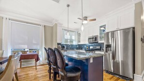 A modern kitchen with a central island, stainless steel appliances, and a dining area with leather chairs. - Elegant Home in Prime Location/ Close to Universities, Hospitals, Parks and Stadiums (Atlanta)