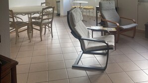 Un'ampia zona giorno con tavolo da pranzo, due sedie, un divano e una lampada da terra.