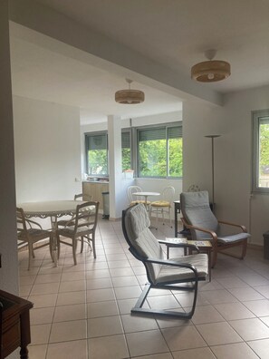 Un vaste espace de vie comprenant une table à manger, deux chaises, un canapé et un lampadaire.