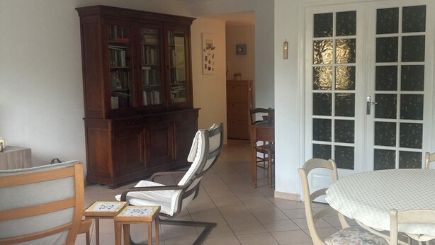 Una stanza con un tavolo da pranzo, sedie, una libreria e una porta con pannelli trasparenti satinati.