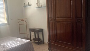 Una camera da letto con un letto, un armadio, un tavolino e una ventola a soffitto.