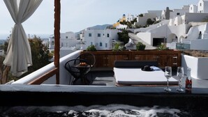 En tagterrasse med udsigt til hvide bygninger, et træterrasse og en hvid sofa.