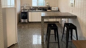 Una cuina amb parets de rajola blanca, un taulell de granat i electrodomèstics d'acer inoxidable, amb vistes per les finestres.