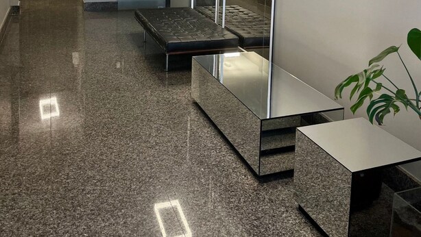 Habitació d'hotel moderna amb un mirall gran, un sofà, una taula petita i una planta.