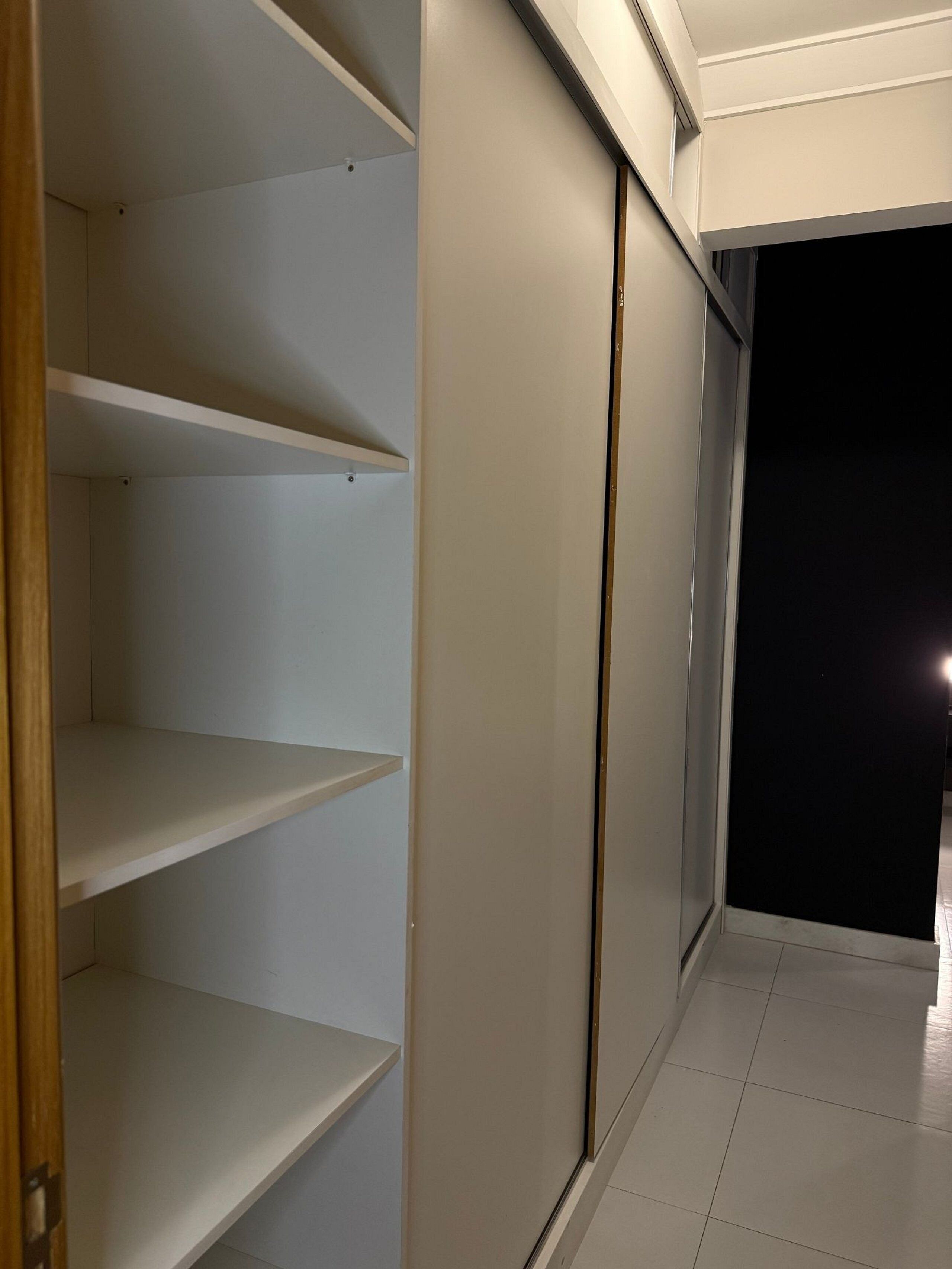 Un couloir avec un placard, une porte et un sol carrelé.