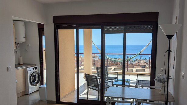 Um apartamento moderno com cozinha, área de refeições e varanda com vista para o mar.