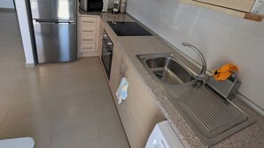 Uma cozinha moderna com eletrodomésticos de aço inoxidável, armários de madeira, bancada de granito e máquina de lavar embutida.