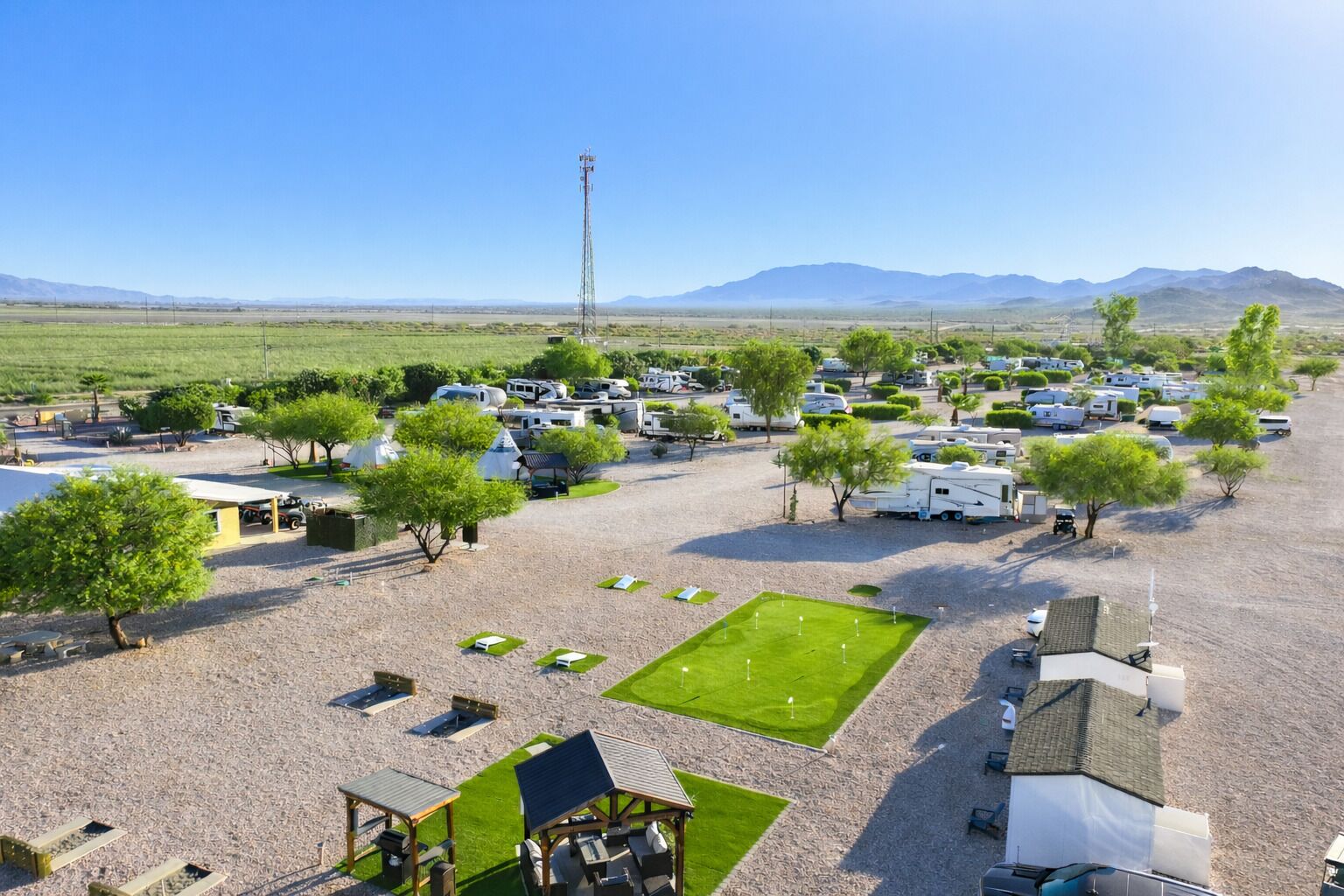 Un terrain de camping équipé d’emplacements pour camping-cars, de zones de pique-nique et offrant une vue dégagée sur les montagnes.