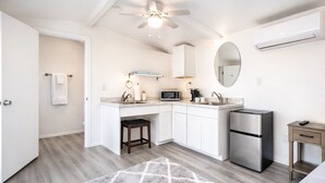 A modern kitchen with a built-in microwave, a stainless steel refrigerator, and a small wooden table.