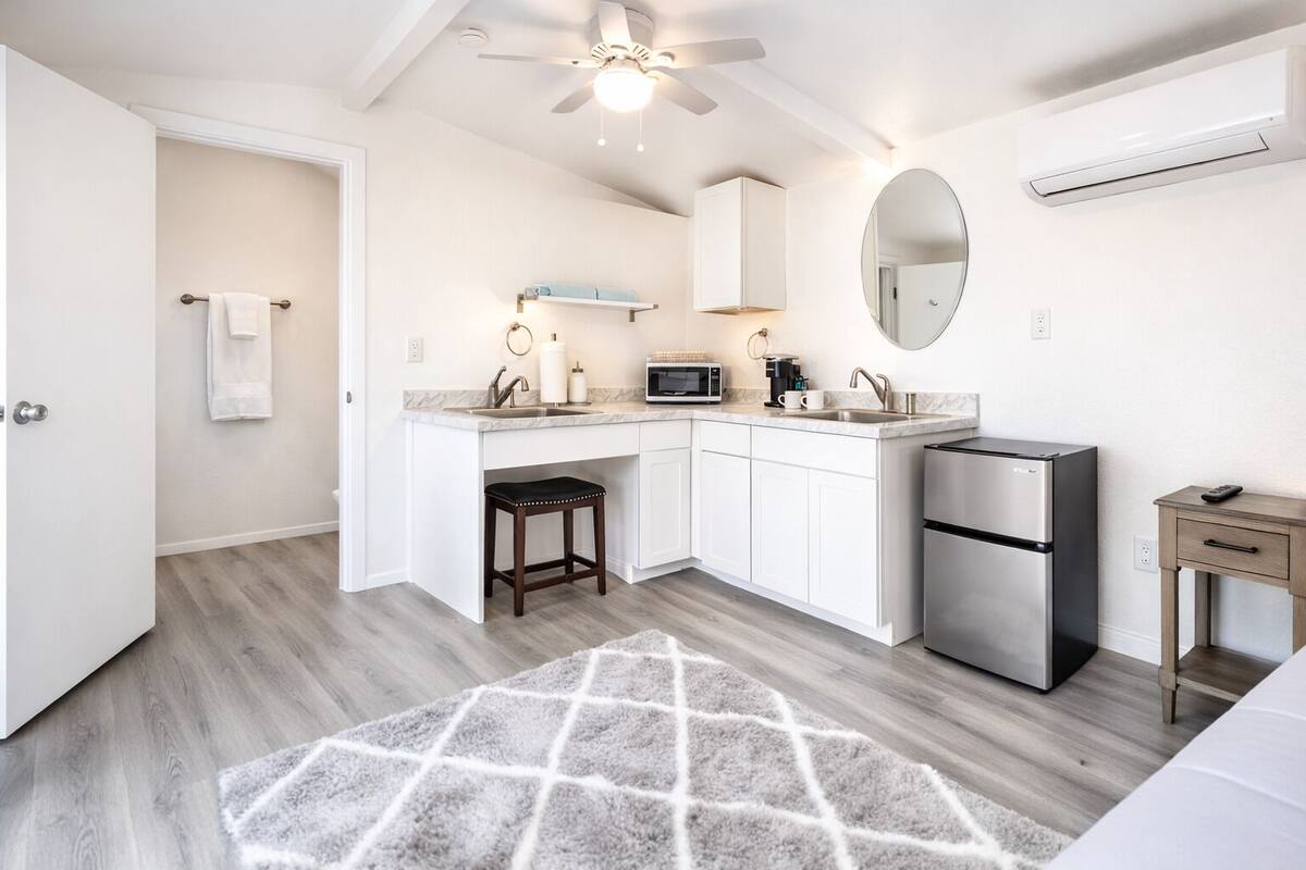 A modern kitchen with a built-in microwave, a stainless steel refrigerator, and a small wooden table.