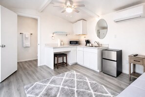 A modern kitchen with white cabinetry, a stainless steel refrigerator, a microwave, and a coffee maker. - The Cabins at Indian Hills (Salome)