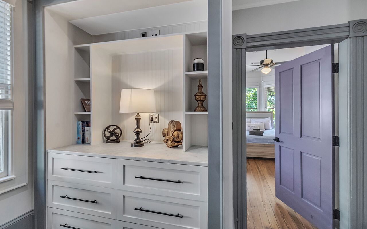 Ein begehbarer Kleiderschrank mit weißen Schränken, einer Lampe und Dekorationselementen.