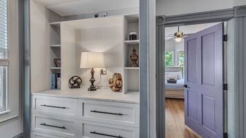 Ein begehbarer Kleiderschrank mit weißen Schränken, einer Lampe und Dekorationselementen.