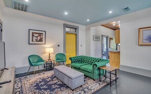 A living room with a green sofa, two chairs, a small table, and a lamp. - Charming 2-bedroom, 2 bath w/ Porches • Walk to Forsyth Park (Savannah)
