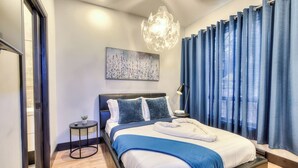 A modern bedroom with a bed, a bedside table, a lamp, a painting, and a view of the outdoors. - Stylish 5BR in Plateau Sleeps 10 (Montreal)