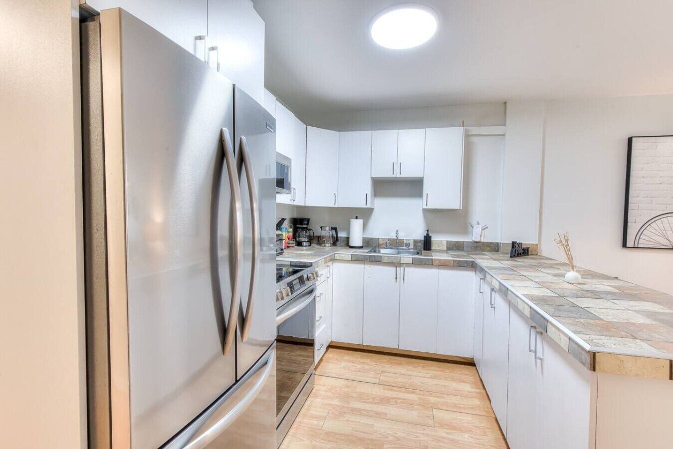 Een moderne keuken met witte kastjes, roestvrijstalen apparatuur en een betegelde achterwand.
