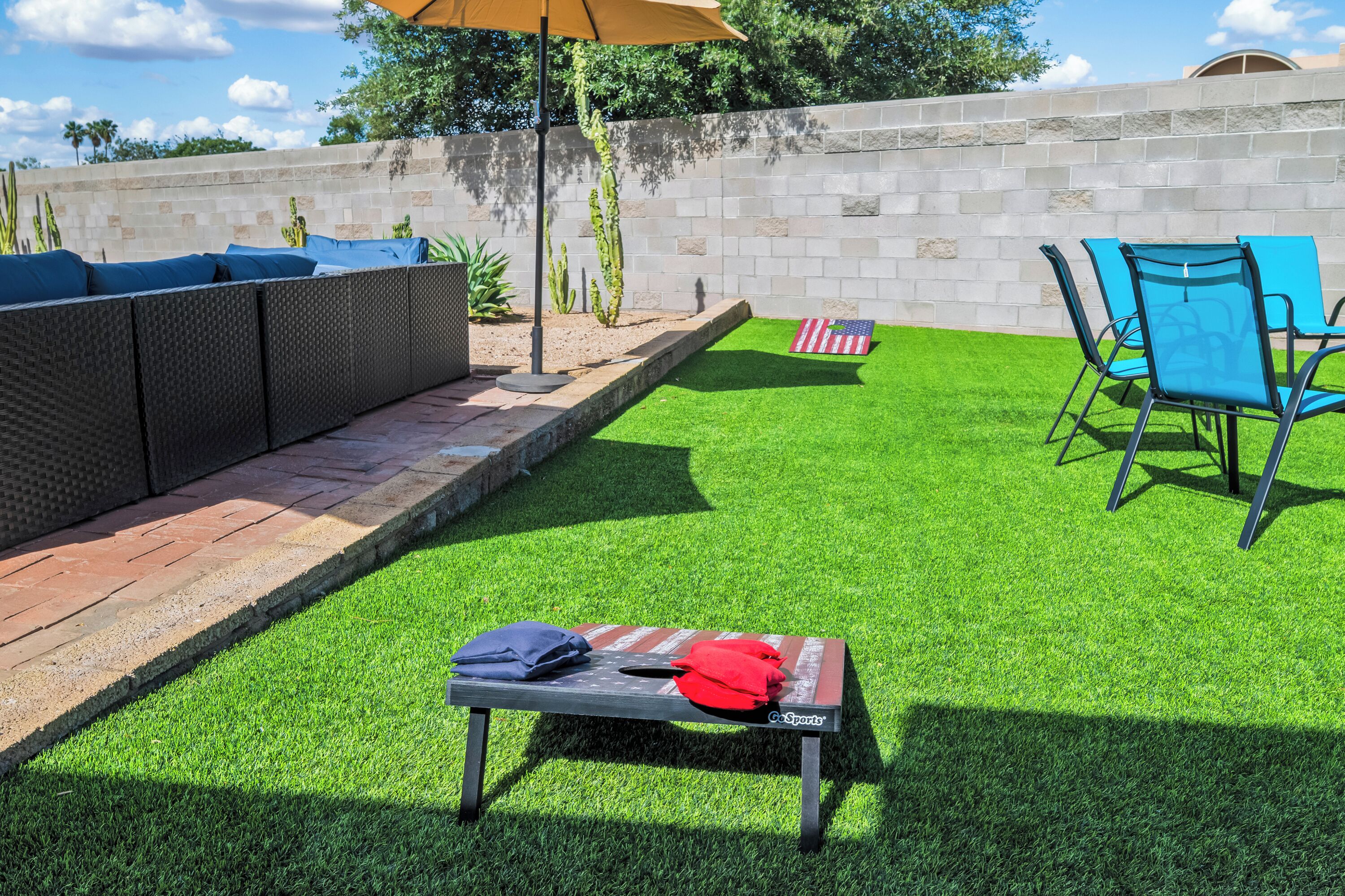 A patio with a table, chairs, and an American flag on artificial grass.