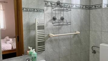 Un baño con lavamanos, inodoro, toallero y espejo.