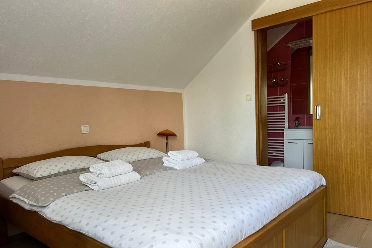 A bedroom with a bed, pillows, a lamp, and a wooden wardrobe.