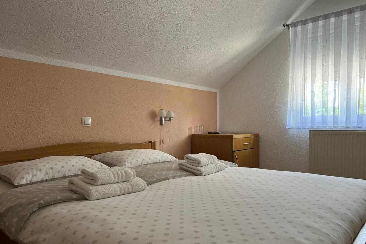 A bedroom with a bed, a nightstand, a lamp, and a window with curtains.