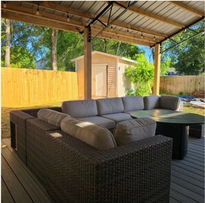 Eine Terrassengruppe im Freien mit einem Korbsessel, einem runden Tisch und einer Pergola mit Lichterketten.