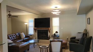 Una sala de estar con chimenea, televisor, sofá, sillón y mesa de centro.