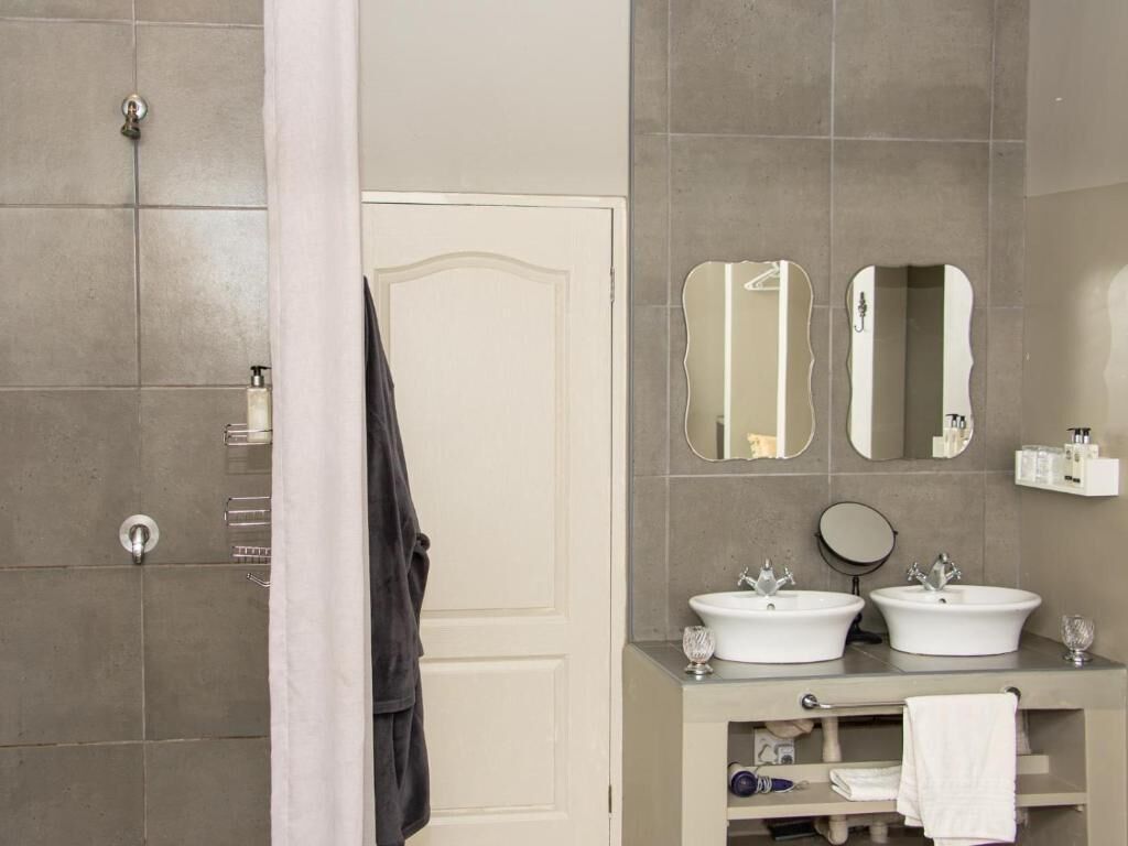 A bathroom with two sinks, a shower, and a door.