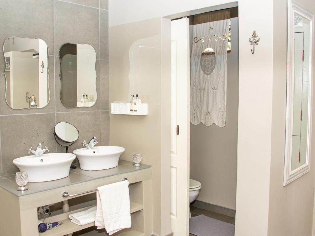 Ein Badezimmer mit zwei Waschbecken, einem Spiegel, einer Duschvorhang und einer Toilette.