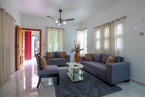 A living room with a sofa, armchair, coffee table, and a ceiling fan.