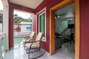 Une pièce dotée d’un balcon, d’un escalier et d’un coin repas avec des chaises.