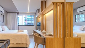 Habitación de hotel con dos camas, un escritorio, una silla y vistas amplias de la ciudad.