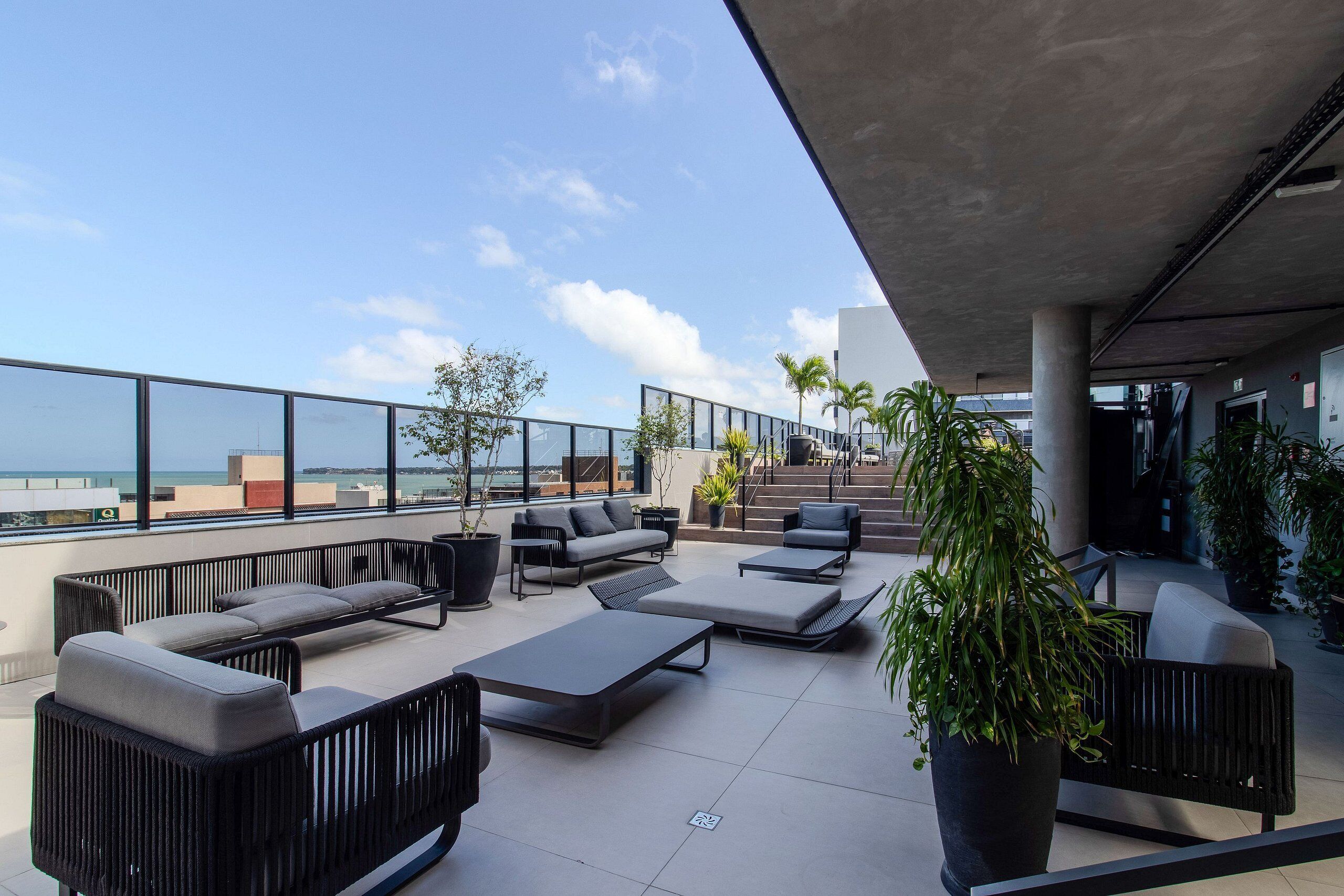 A rooftop terrace with outdoor seating, potted plants, and a view of the cityscape.