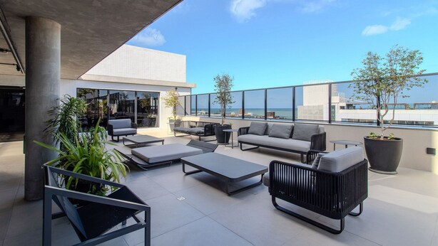 Terraza en la azotea con mobiliario exterior, plantas en macetas y vistas al horizonte de la ciudad.