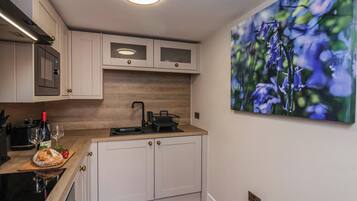 A modern kitchen with white cabinetry, a wooden countertop, a built-in oven, and a wall-mounted picture of flowers.