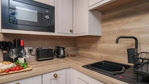 A modern kitchen with white cabinets, a black microwave, a toaster, and a sink. - Little Holm Garth (Whitby)